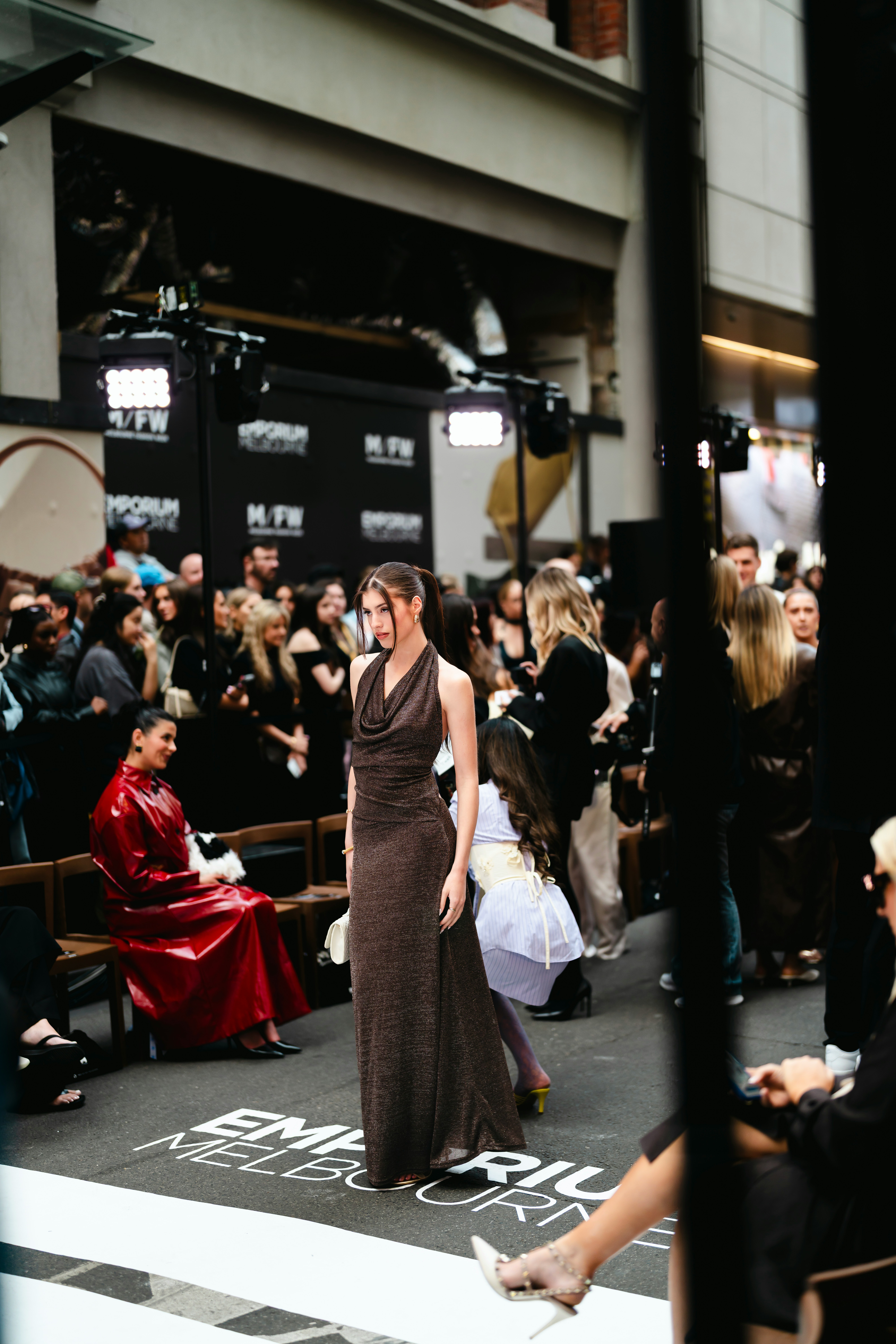 A fashion model walking through an event space with audience and lighting