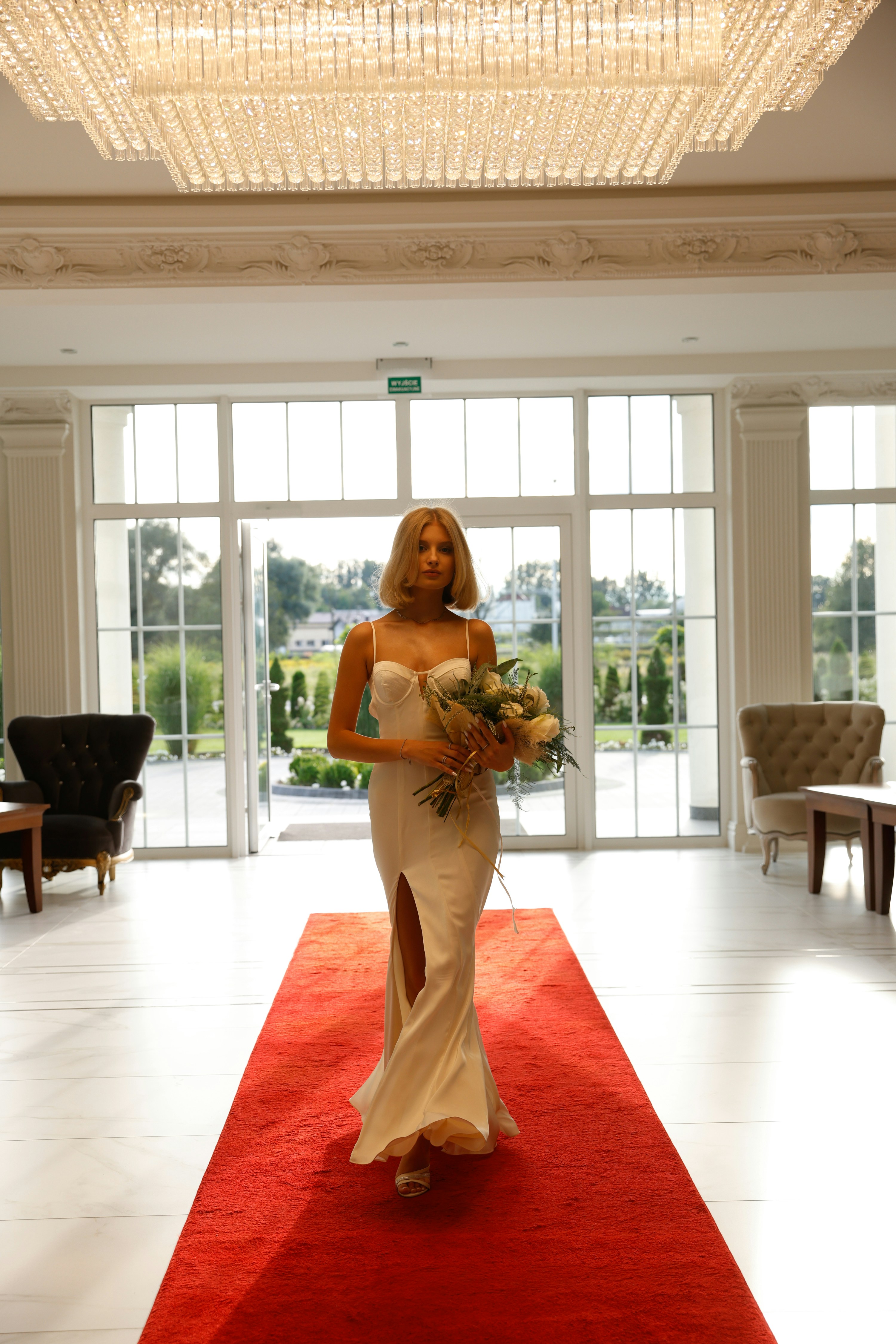 An elegant model in a white dress standing on a red carpet